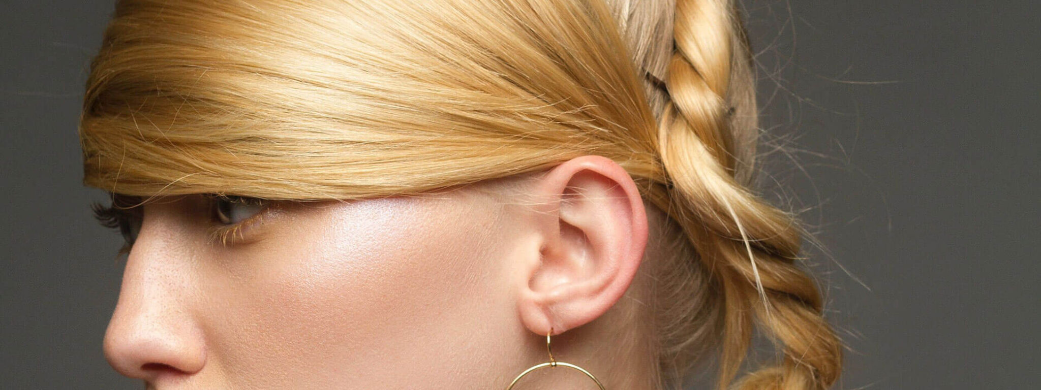 Porträt einer Frau mit aufwendiger, geflochtener Hochsteckfrisur und Schmuck, geeignet für einen Hairstyling-Workshop.