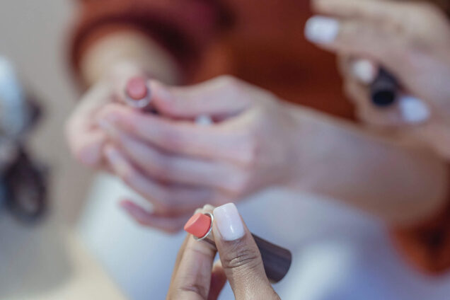 Handnahaufnahme während einer Maniküreschulung, bei der Nageldesigns und Techniken demonstriert werden.