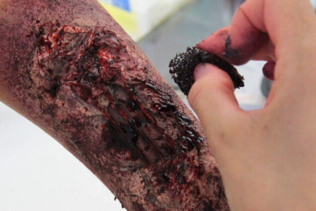 Arm mit realistisch gestalteten Wunden und blutigen Effekten, erstellt im Rahmen eines Special-Effects-Workshops.