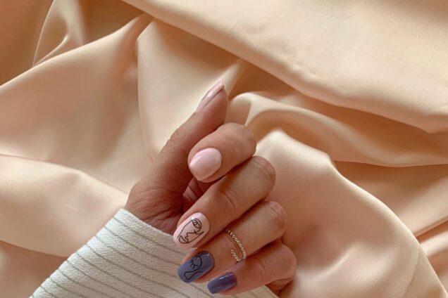 Hand mit gepflegten, blau lackierten Nägeln auf weichem Stoff, Beispiel für Nageldesign und Maniküre bei Beauty & Style Academy