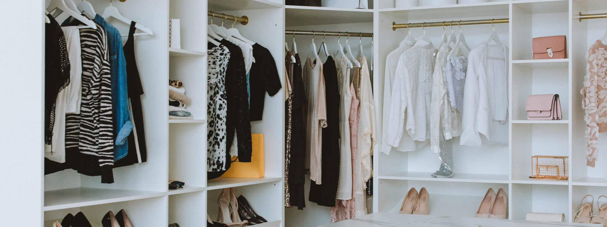 Großer begehbarer Kleiderschrank mit Schubladen, hängender Kleidung und Schuhregalen.