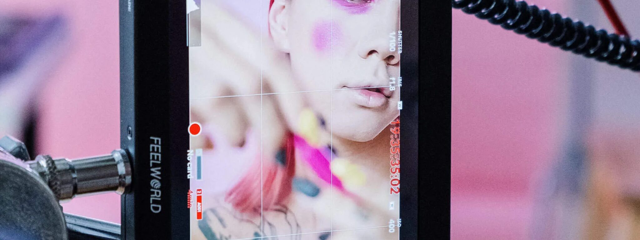 Make-up-Künstlerin bei der Arbeit, die auf einem Bildschirm in Echtzeit für das Beauty & Style Academy Referenzen-Shooting überwacht wird.
